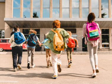 School children, students walking into a school building.